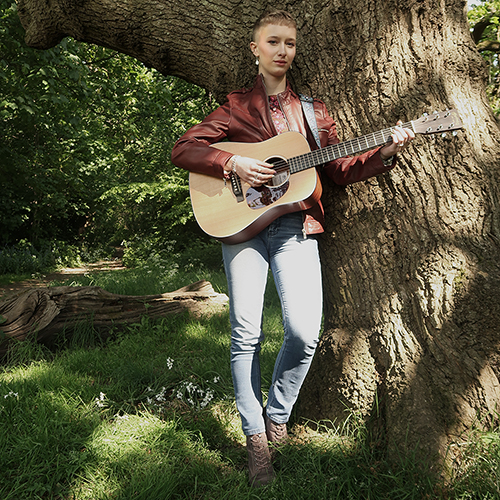 Zara playing guitar in the woods.